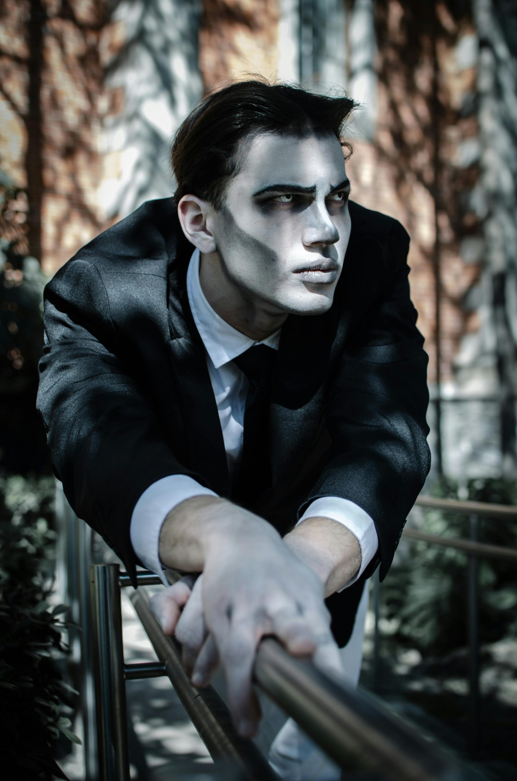 Homme en cosplay gothique avec un maquillage dramatique en extérieur, capturant une essence théâtrale.