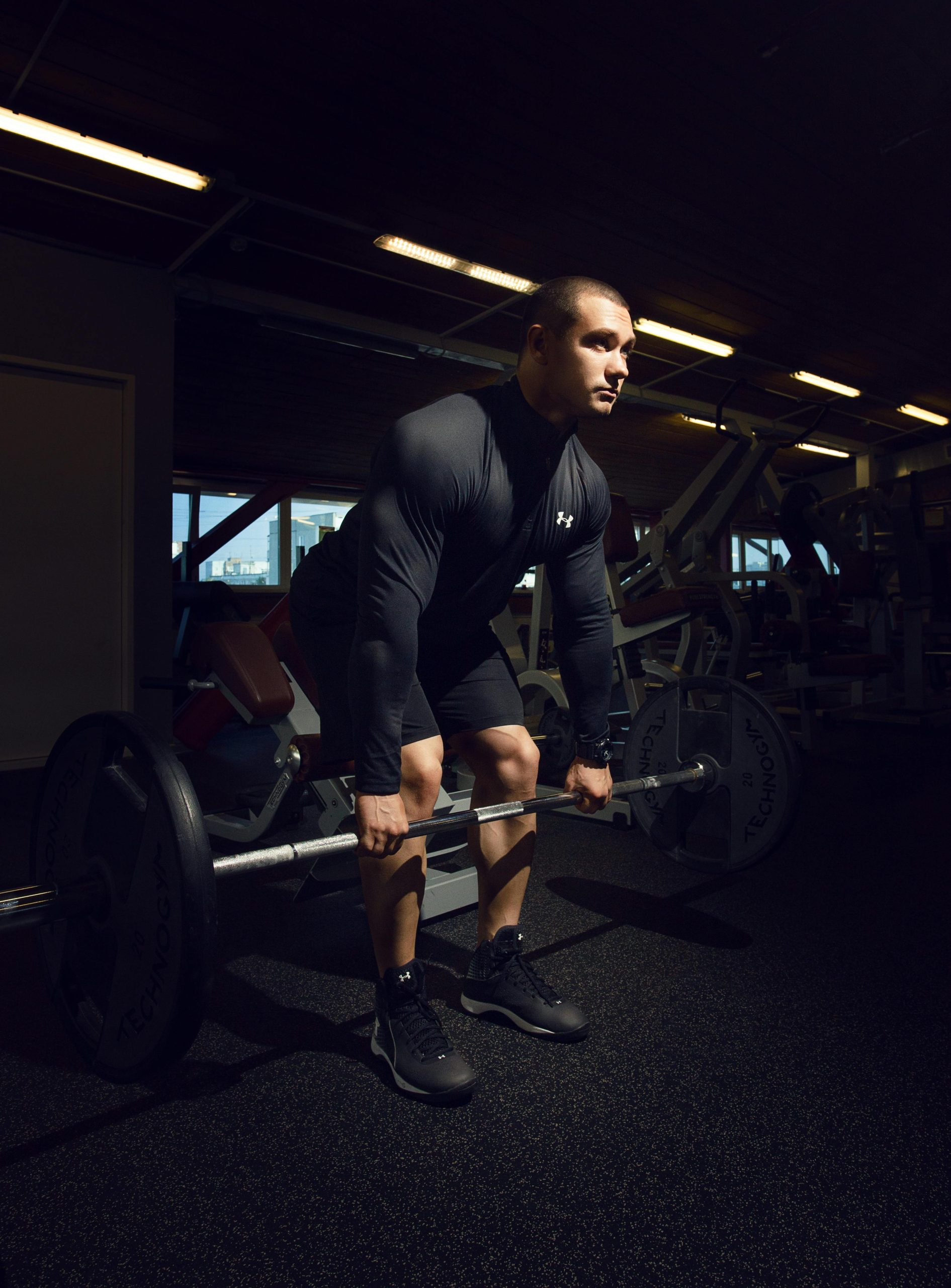 Musculaire soulevant une barre lourde en salle de sport pendant un entraînement, démontrant force et concentration.
