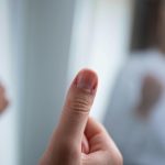 A focused shot of a hand making a thumbs up gesture, symbolizing approval or success. Un gros plan d'une main faisant un geste de pouce levé, symbolisant l'approbation ou le succès.