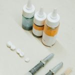 From above of assorted bottles and tools for making fake tooth near dental implants placed on white table in light dental clinic Vue de dessus de bouteilles assorties et d'outils pour la fabrication de fausses dents près d'implants dentaires placés sur une table blanche dans une clinique dentaire lumineuse.
