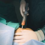 Doctor performs injection procedure, highlighting healthcare precision. Un médecin effectue une procédure d'injection, mettant en évidence la précision des soins de santé.