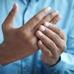 Close-up of a man gently holding his hand, symbolizing comfort or pain relief. Gros plan d'un homme tenant doucement sa main, symbolisant le confort ou le soulagement de la douleur.