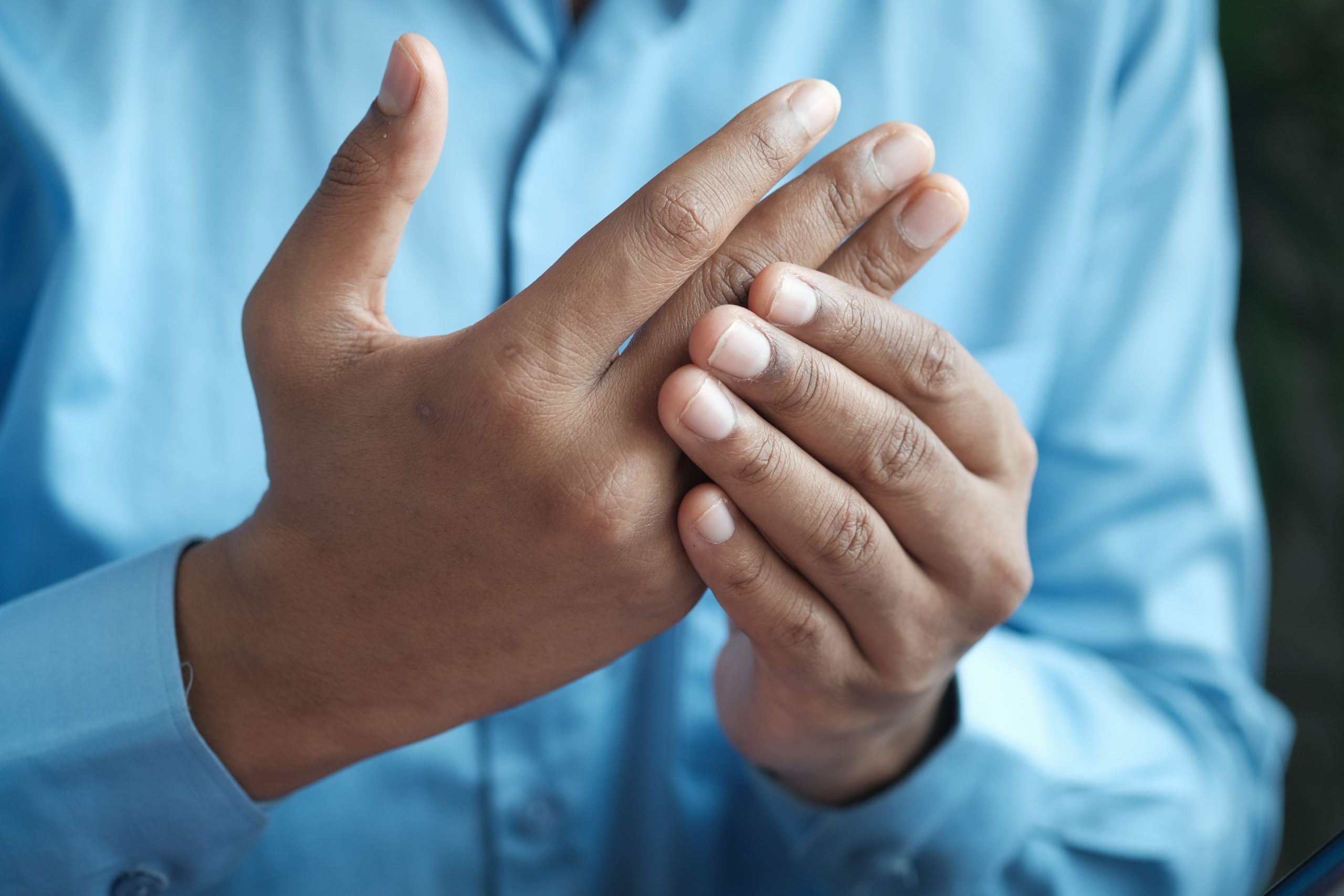 Close-up of a man gently holding his hand, symbolizing comfort or pain relief. Gros plan d'un homme tenant doucement sa main, symbolisant le confort ou le soulagement de la douleur.
