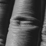 Detailed macro shot showcasing the intricate texture and pattern of wrinkled human skin in black and white. Gros plan macro détaillé mettant en évidence la texture complexe et les motifs de la peau humaine ridée en noir et blanc.