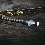 Close-up of a discarded syringe on a rough surface highlighting addiction issues. Gros plan d'une seringue jetée sur une surface rugueuse mettant en évidence les problèmes de dépendance.