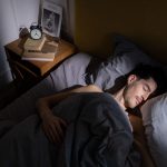 A man peacefully sleeping in bed with morning sunlight streaming in, creating a serene indoor scene. Un homme dormant paisiblement dans son lit avec la lumière du matin qui filtre, créant une scène intérieure sereine.