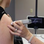 Healthcare professional conducting an ultrasound on a shoulder injury in a medical office. Professionnel de la santé effectuant une échographie sur une blessure à l'épaule dans un cabinet médical.