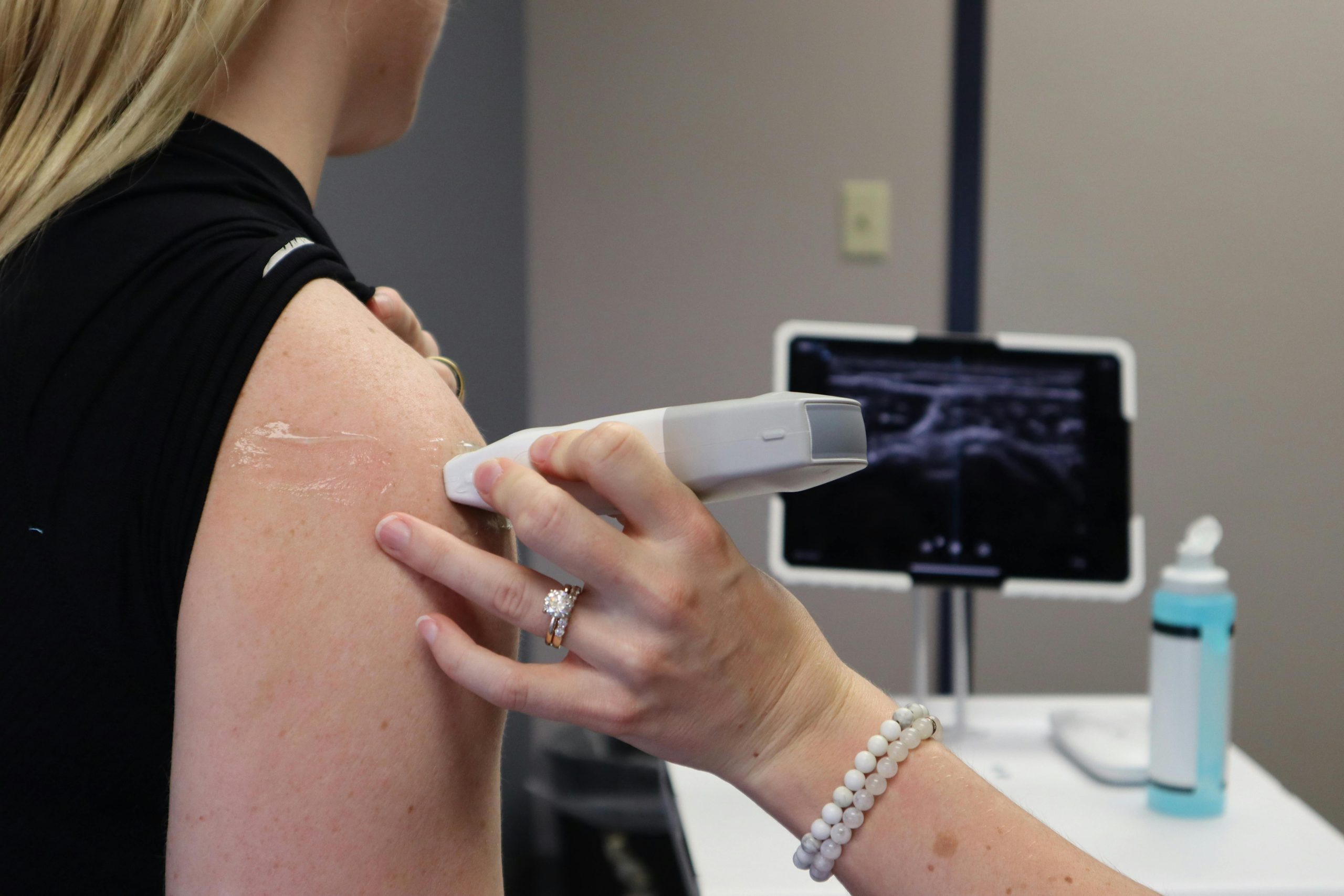 Healthcare professional conducting an ultrasound on a shoulder injury in a medical office. Professionnel de la santé effectuant une échographie sur une blessure à l'épaule dans un cabinet médical.