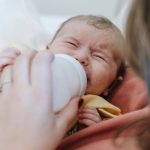 Close-up of a mother feeding her crying newborn with a bottle. Gros plan d'une mère nourrissant son nouveau-né qui pleure avec un biberon.