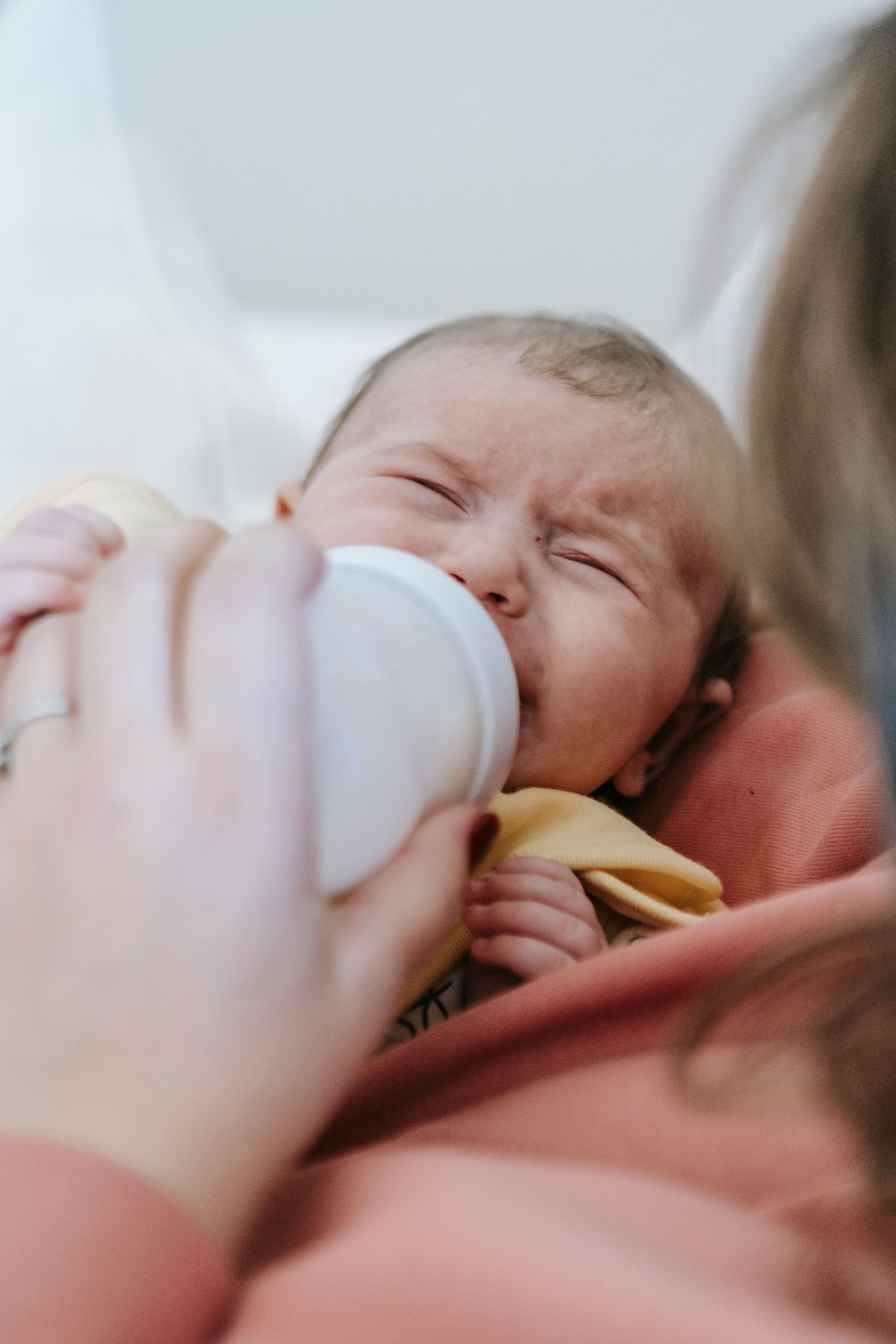 Close-up of a mother feeding her crying newborn with a bottle. Gros plan d'une mère nourrissant son nouveau-né qui pleure avec un biberon.