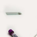 Blood vacutainer with sample and slide on a white background for medical testing. Flacon de prélèvement sanguin avec échantillon et lame sur fond blanc pour test médical.