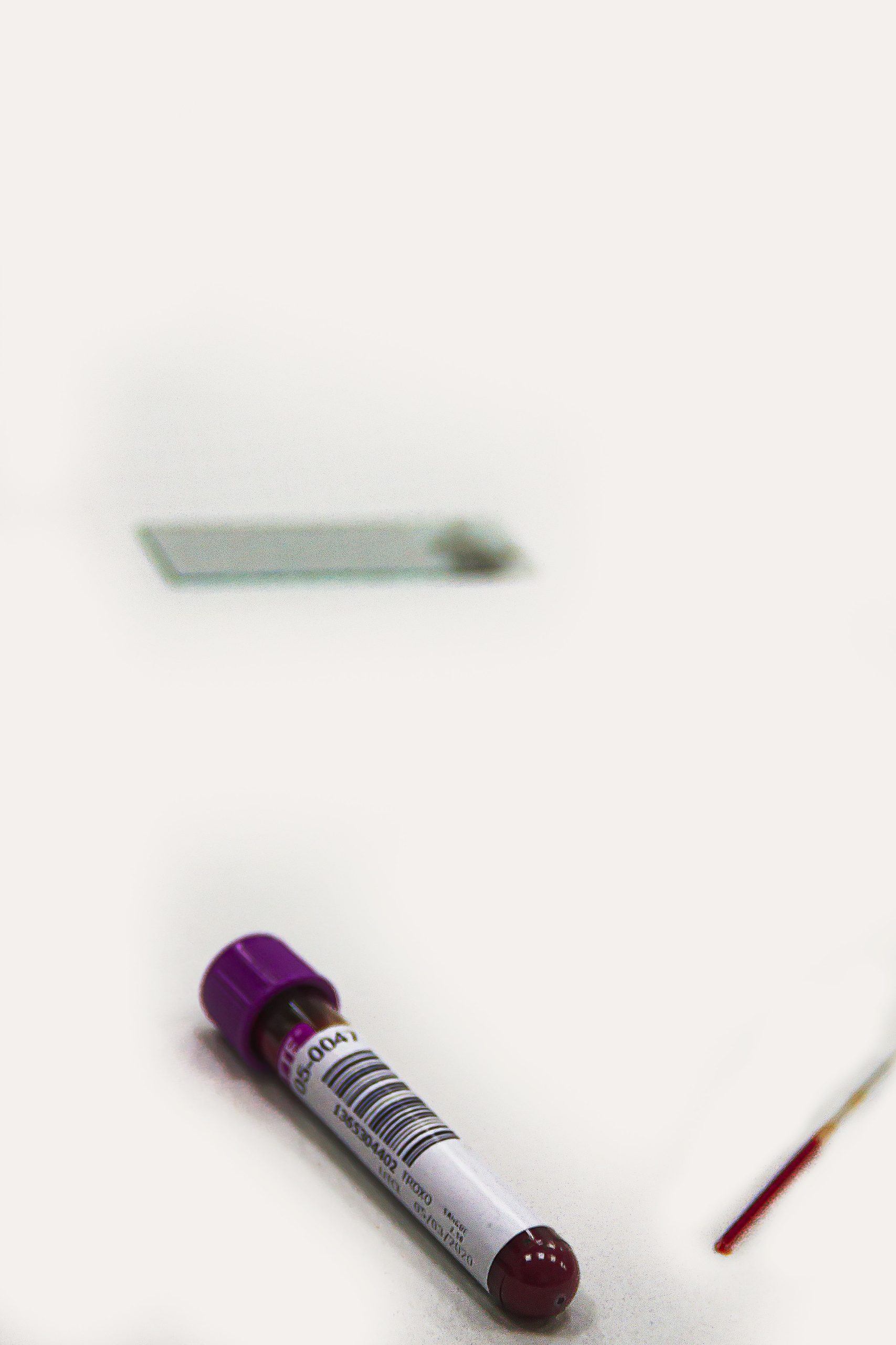 Blood vacutainer with sample and slide on a white background for medical testing. Flacon de prélèvement sanguin avec échantillon et lame sur fond blanc pour test médical.