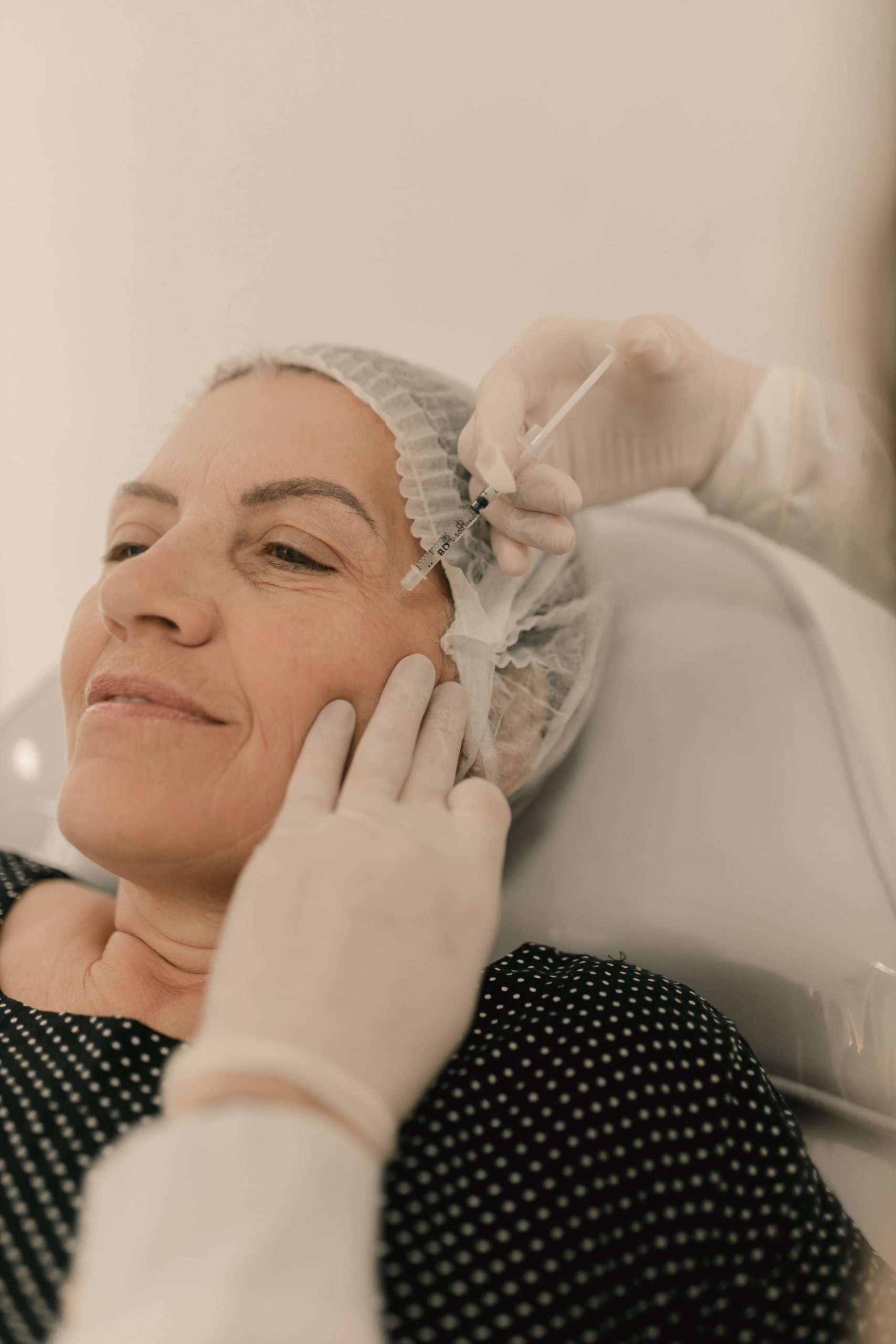 A woman undergoing a facial injection treatment in a medical setting, emphasizing skincare and aesthetics. Une femme subissant un traitement d'injection faciale dans un cadre médical, mettant l'accent sur les soins de la peau et l'esthétique.