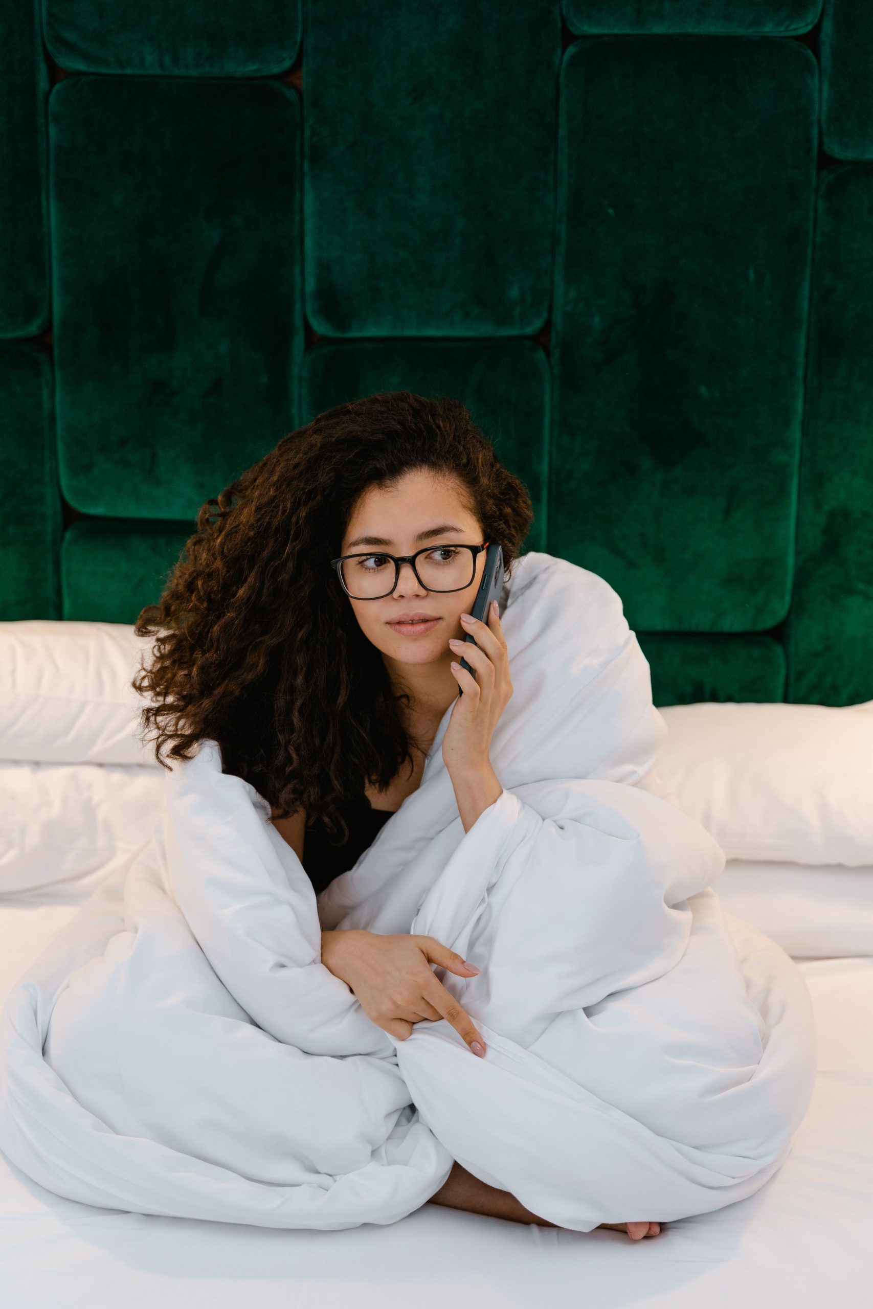 Casual morning call in bed with a woman wrapped in a blanket. Un appel matinal décontracté au lit avec une femme enveloppée dans une couverture.