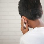 A child is depicted covering their ear, suggesting discomfort or concern. Un enfant est montré se couvrant l'oreille, suggérant un malaise ou une préoccupation.