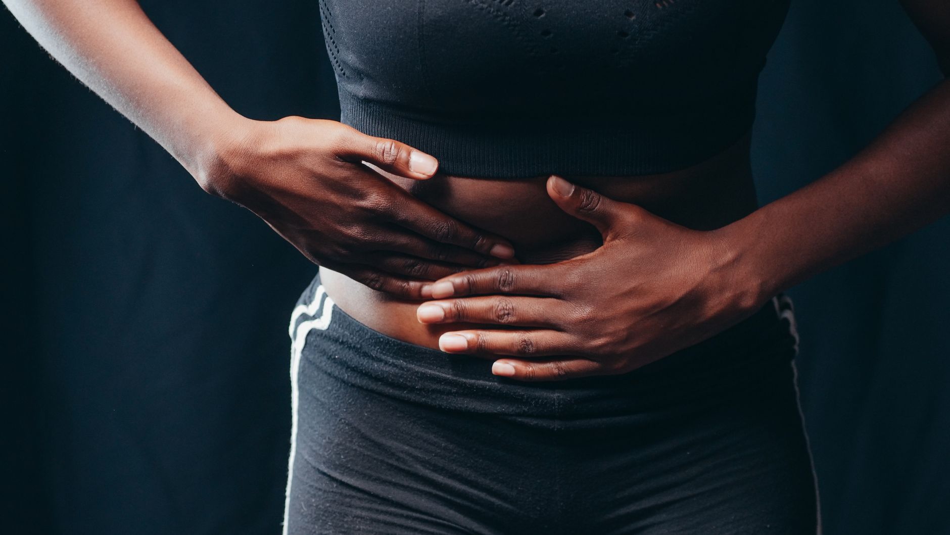 Femme en tenue de sport posant les mains sur son abdomen