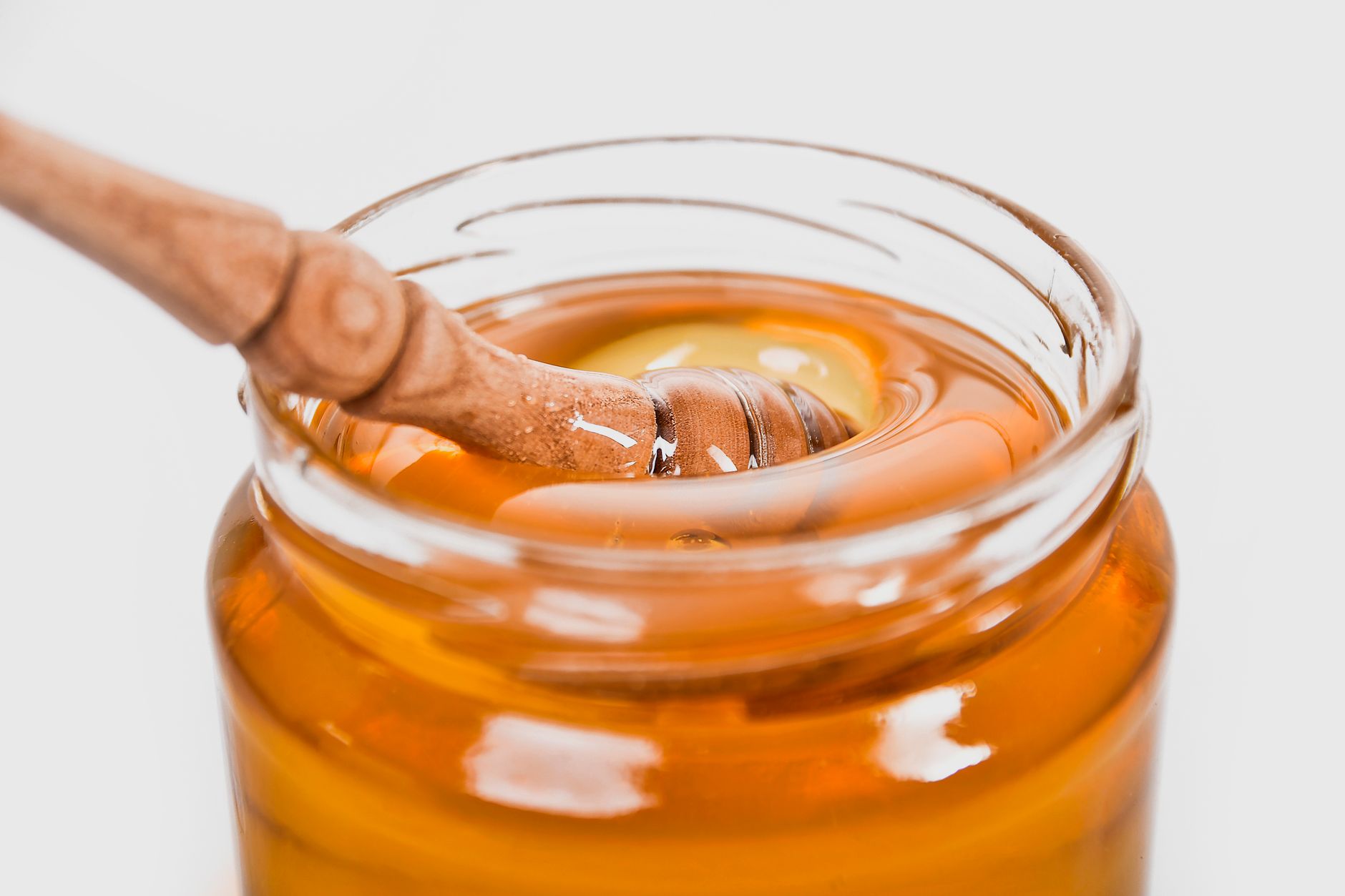 Cuillère à miel plongée dans un pot doré