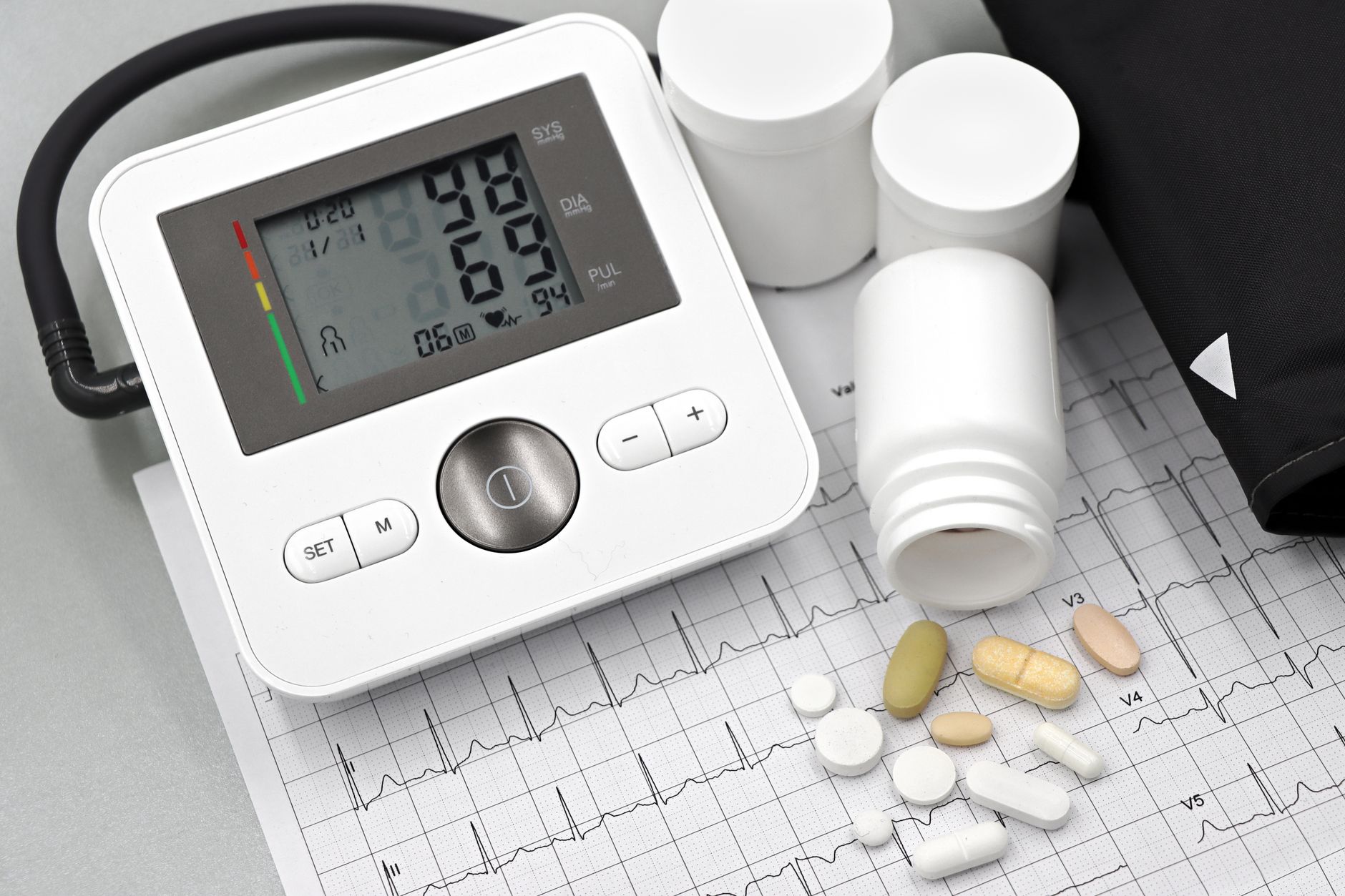 Tensiomètre et comprimés posés sur un tracé ECG