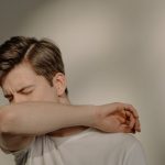 Jeune homme qui tousse dans son coude