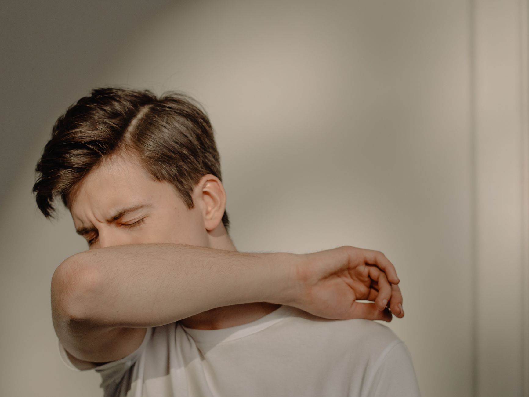 Jeune homme qui tousse dans son coude