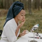 Femme applique une crème sur son visage devant un miroir
