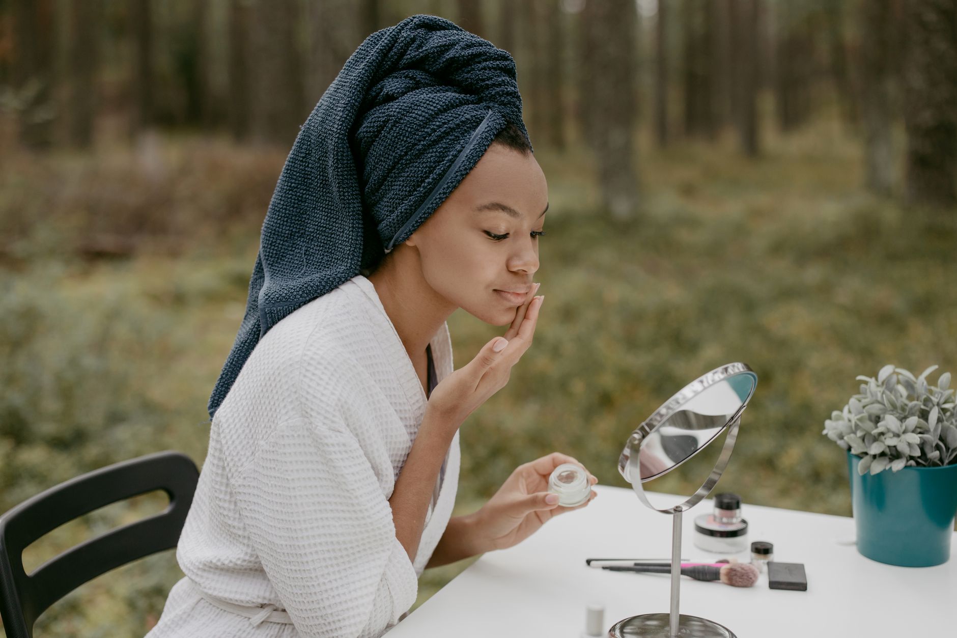 Femme applique une crème sur son visage devant un miroir