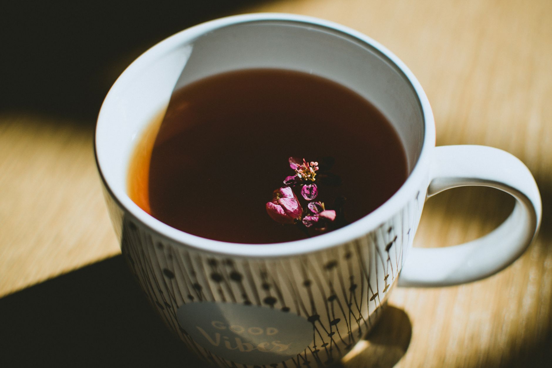 Tasse de tisane fumante posée sur une table en bois
