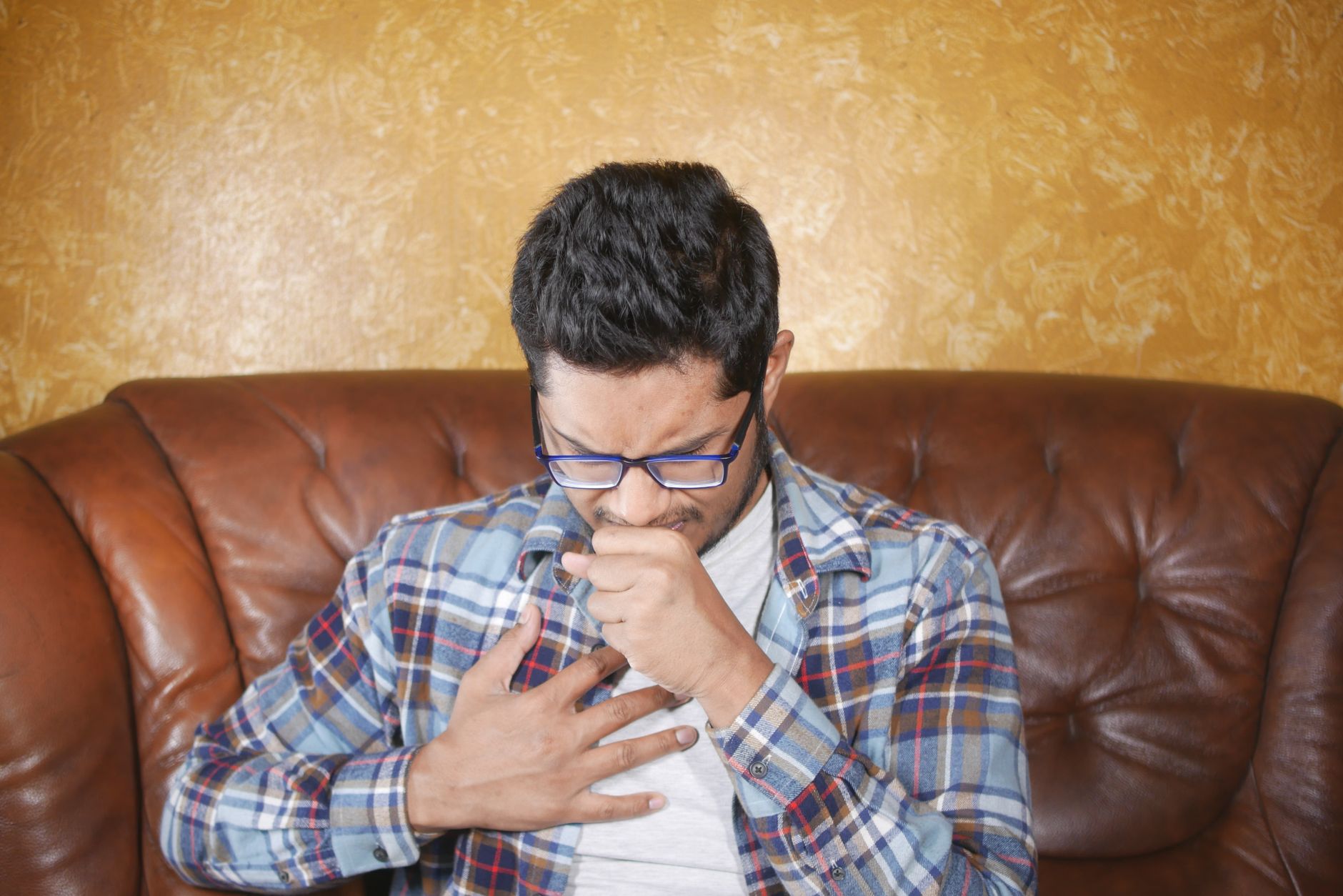 Homme assis qui tousse et se tient le thorax