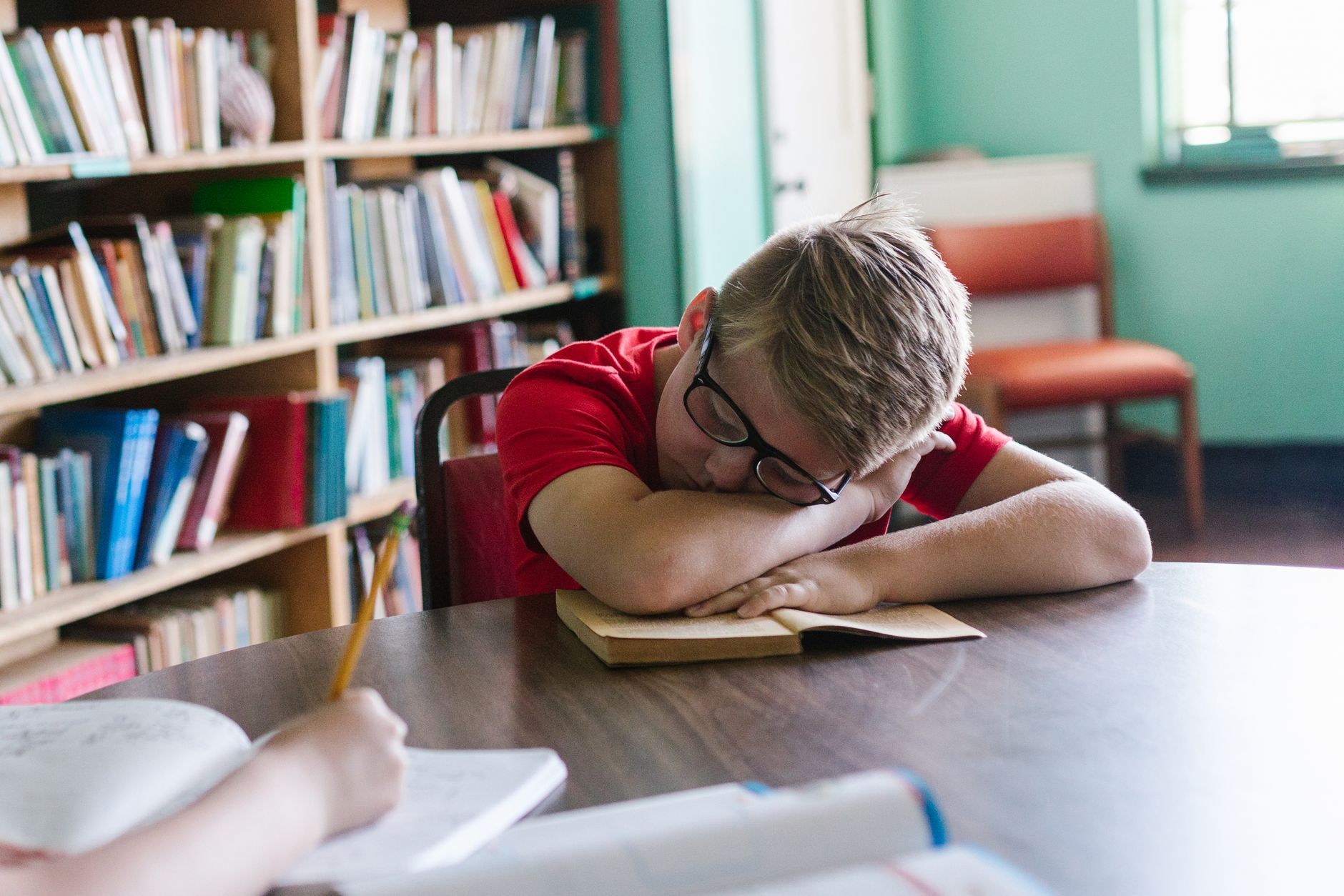 Enfant assis à un bureau qui feuillette un livre