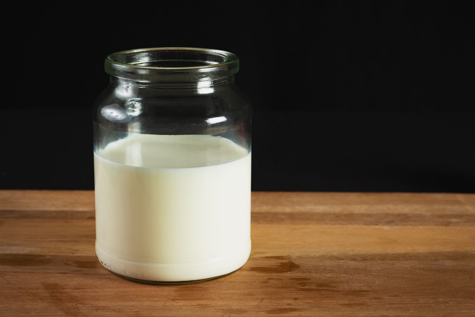 Bocal en verre rempli de lait fermenté sur une table en bois