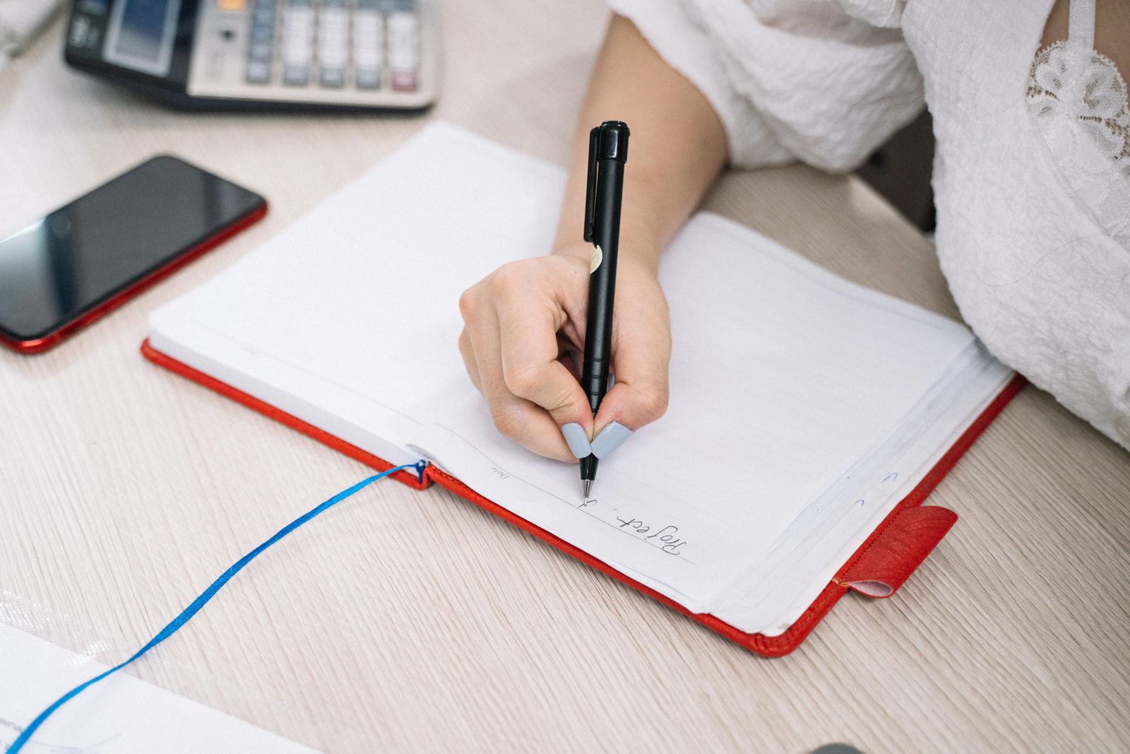 Main qui note ses volontés dans un cahier sur un bureau