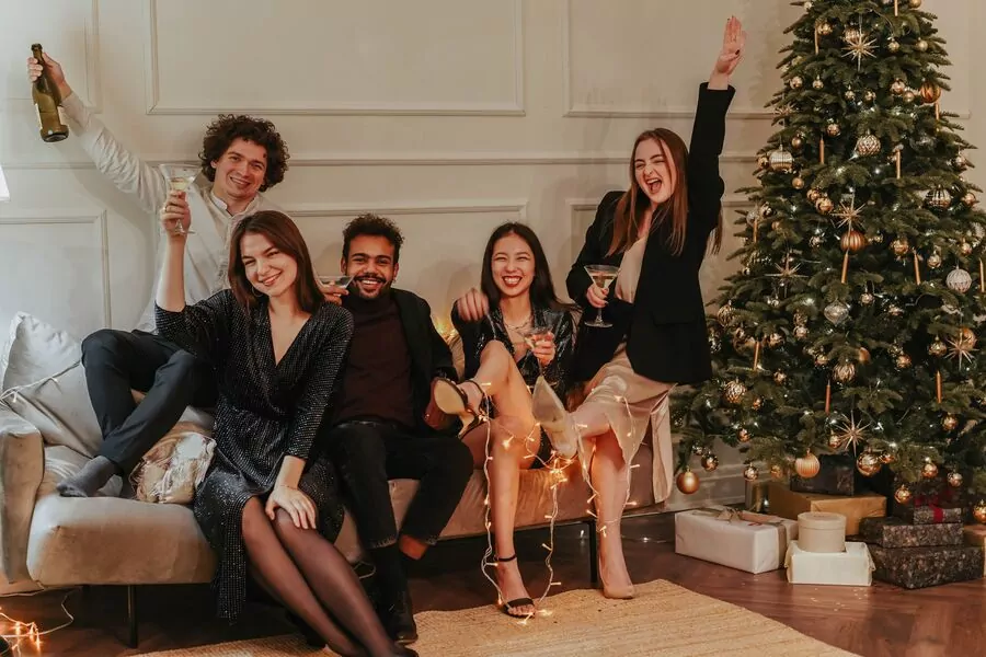 Groupe d amis qui trinquent sur un canapé devant un sapin de Noël