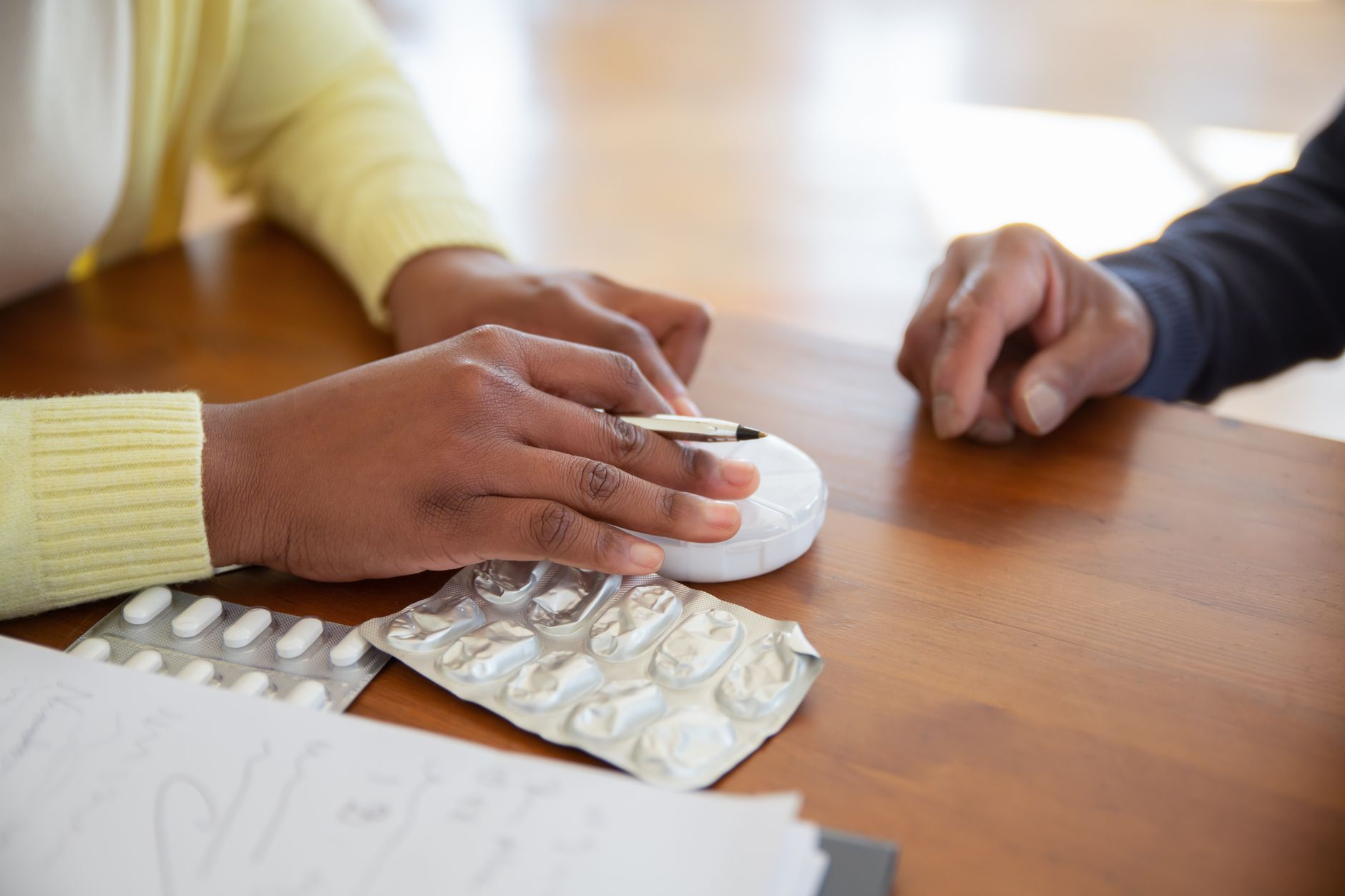 Mains, médicaments et stylo sur une table en bois
