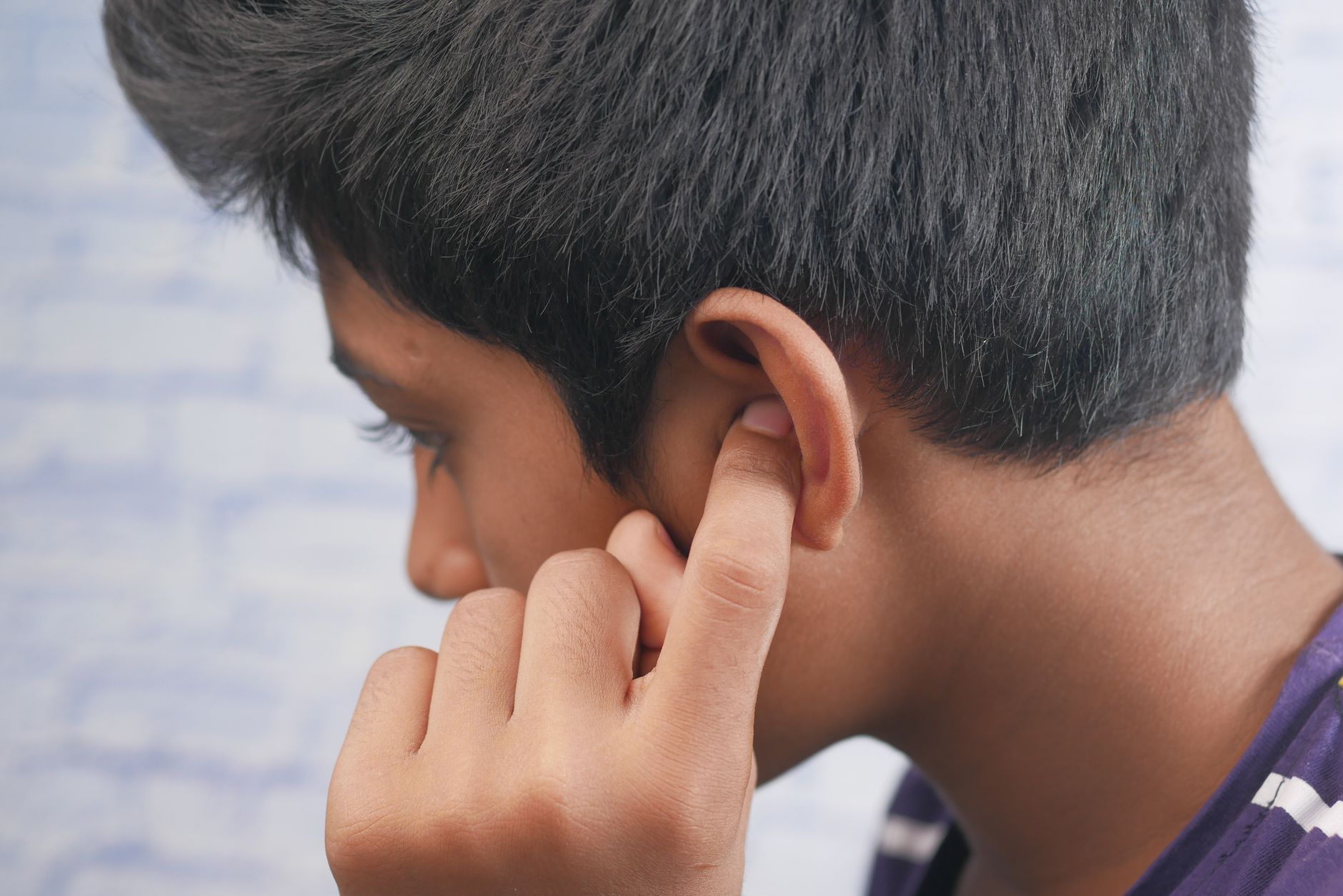 Adolescent portant la main à son oreille