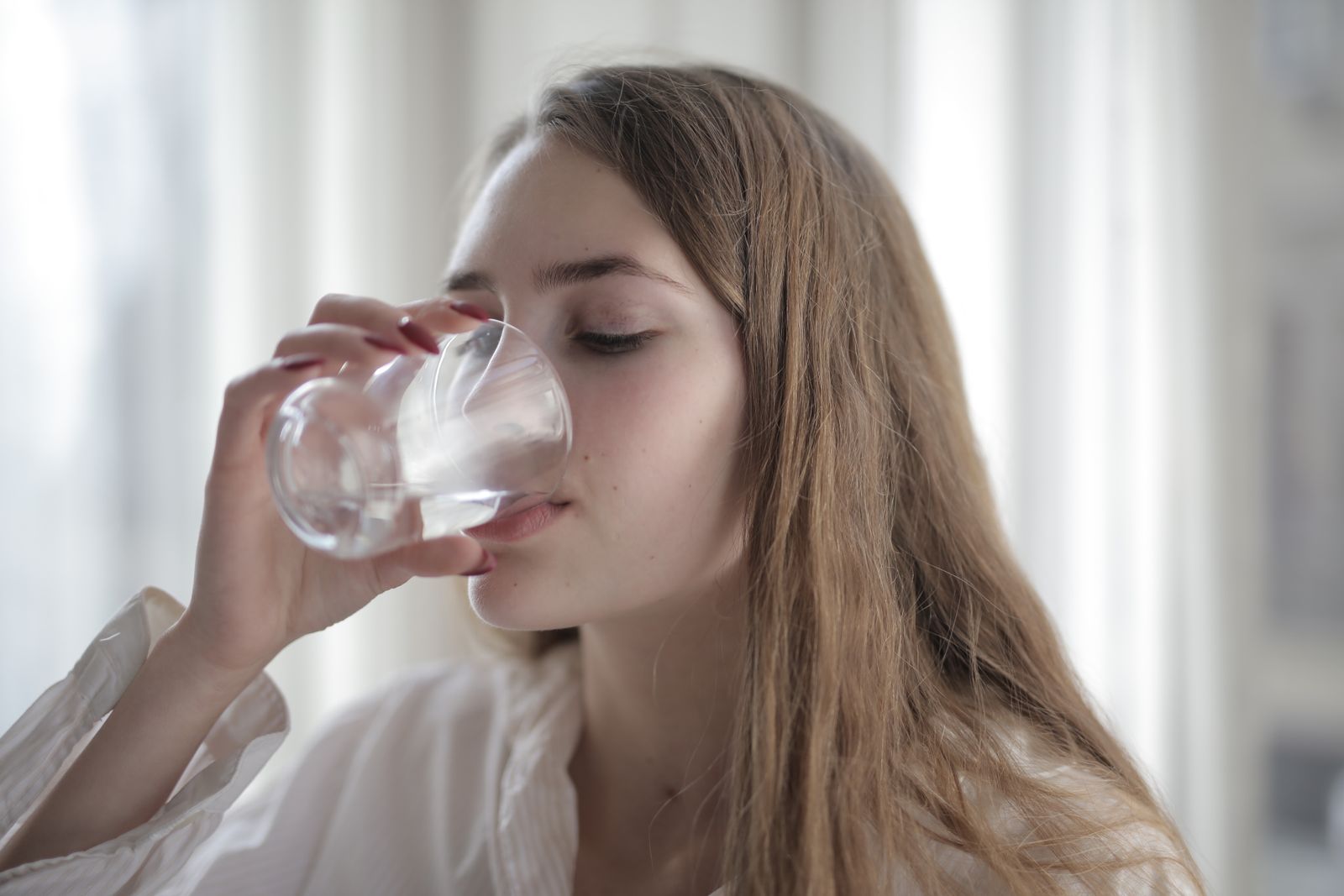 Femme qui boit un grand verre d'eau pour s'hydrater